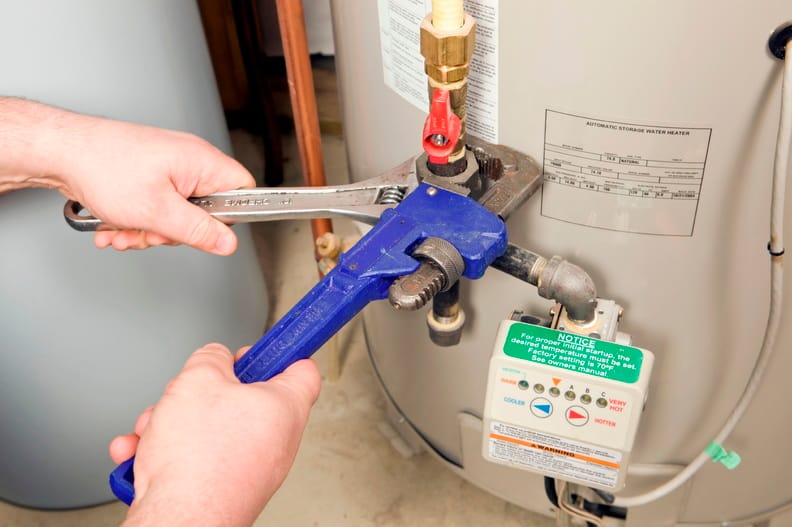 Plumber repairing water heater pipe connection in Mableton, Georgia home