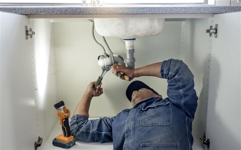 Plumber repairing kitchen sink drain pipes in Mableton, Georgia