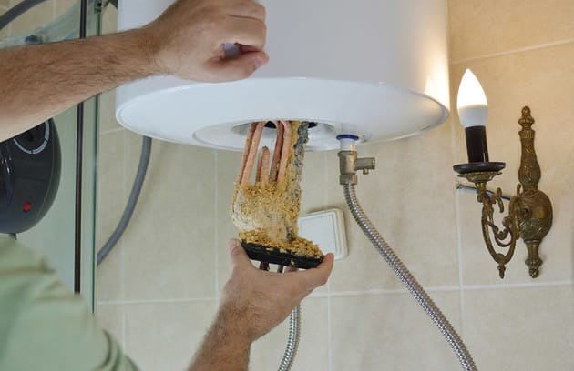 Technician removing mineral buildup from a water heater in Mableton
