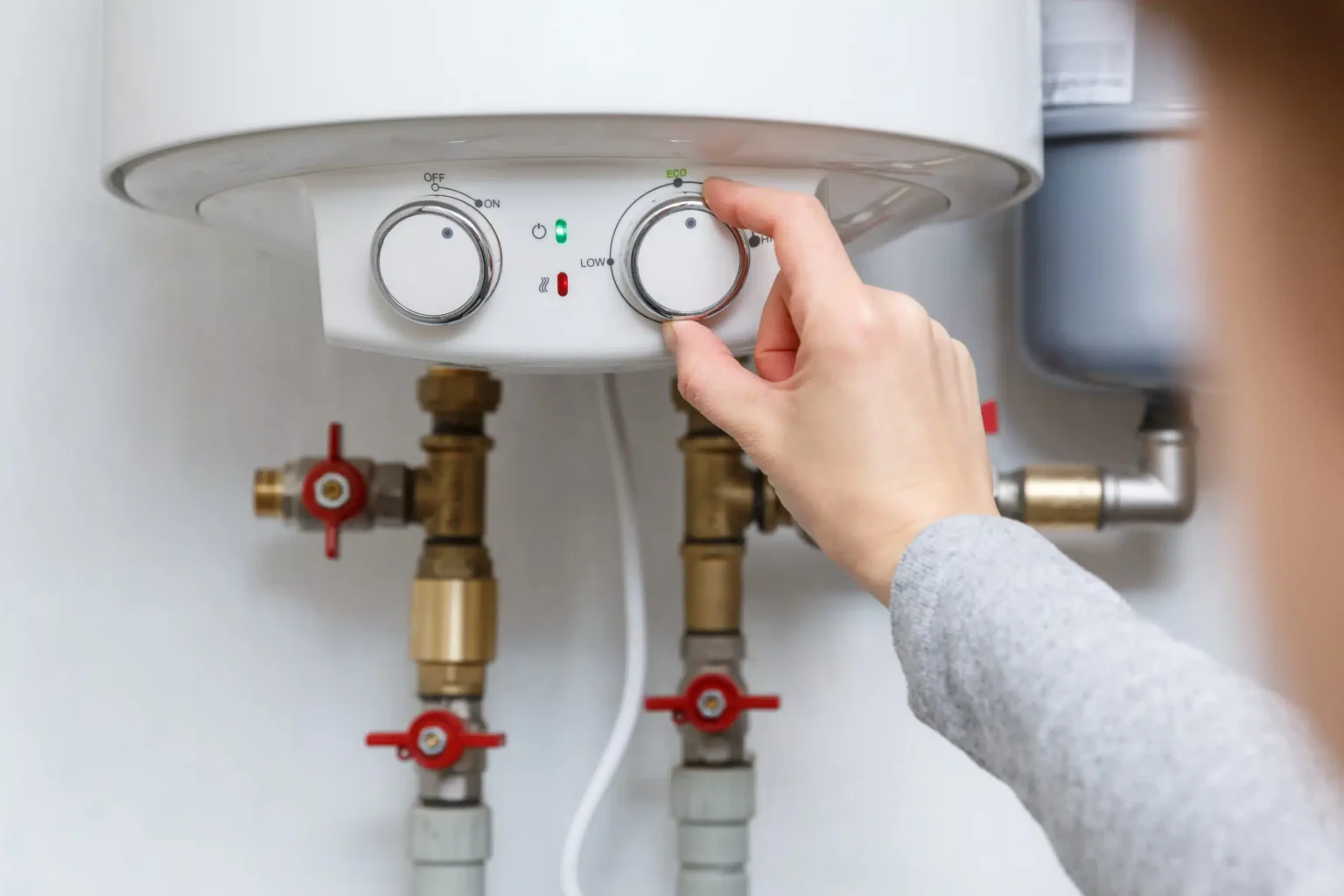 Homeowner adjusting the temperature controls on a water heater in Mableton